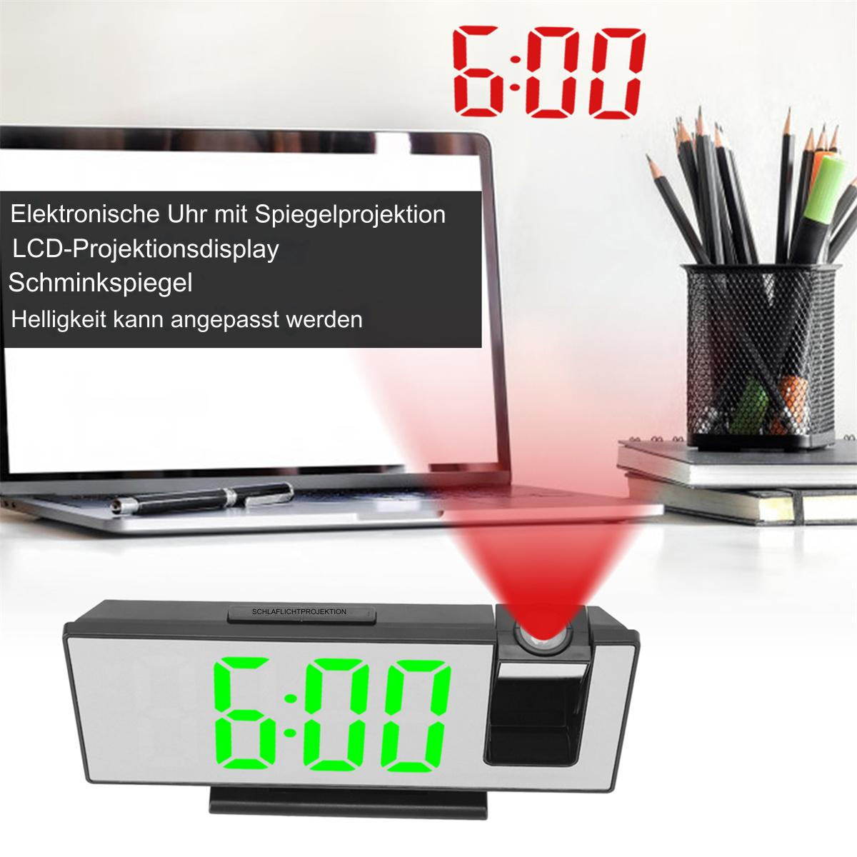 Digitale Uhr zeigt 6:00, rote Projektion, Laptop, Bleistifte. Schwarze Uhr mit grünen Ziffern.