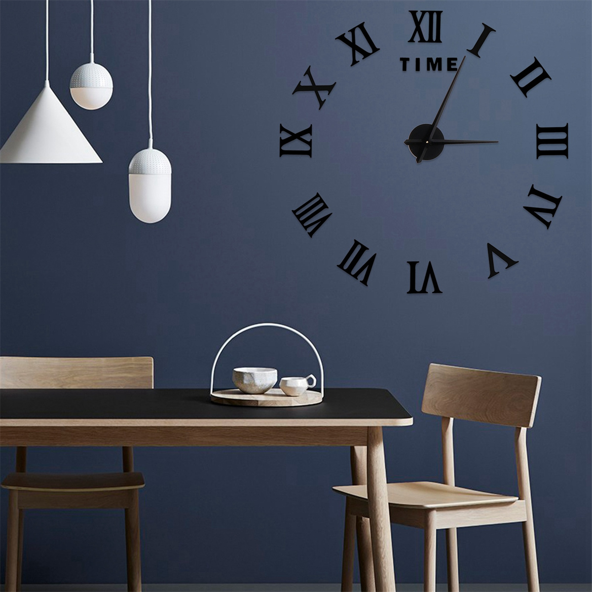 Wanduhr mit römischen Ziffern. Ein Tisch mit Stühlen befindet sich im Vordergrund. Weiße Pendelleuchten hängen oben.