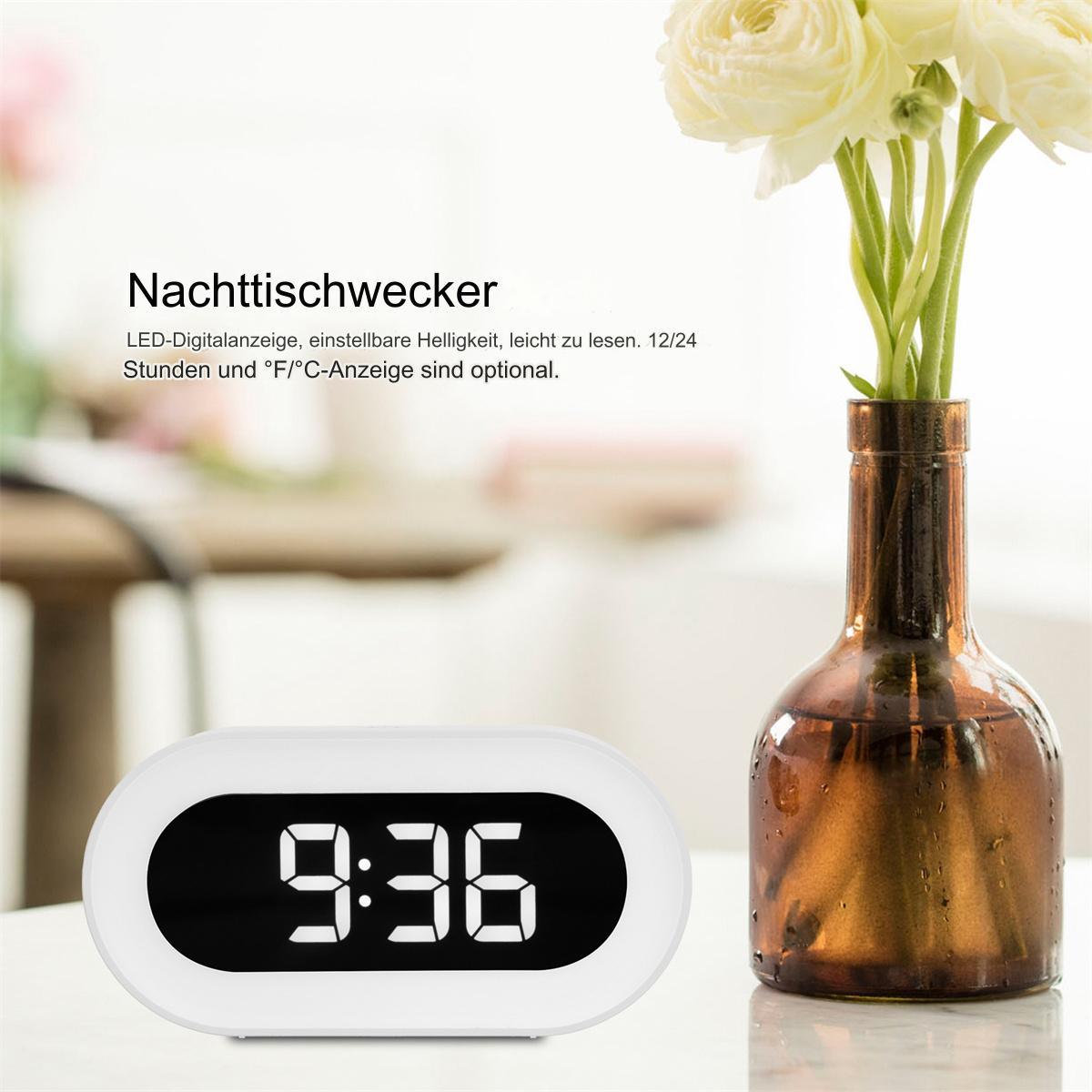 Eine weiße Digitaluhr mit 9:36, rechts eine Vase mit Blumen. Text auf Deutsch oben.