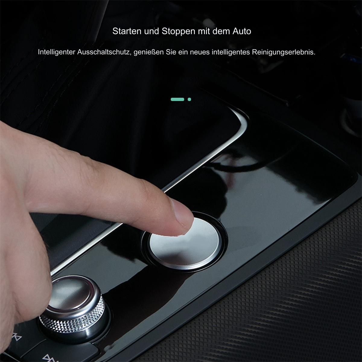 Eine Hand drückt einen silbernen Knopf auf einer schwarzen, glänzenden Oberfläche im Auto.