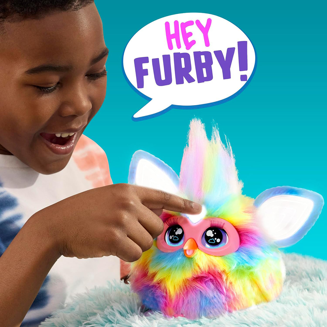 Kind interagiert mit einem bunten Furby-Spielzeug. Das Spielzeug hat große Augen und ist bunt.