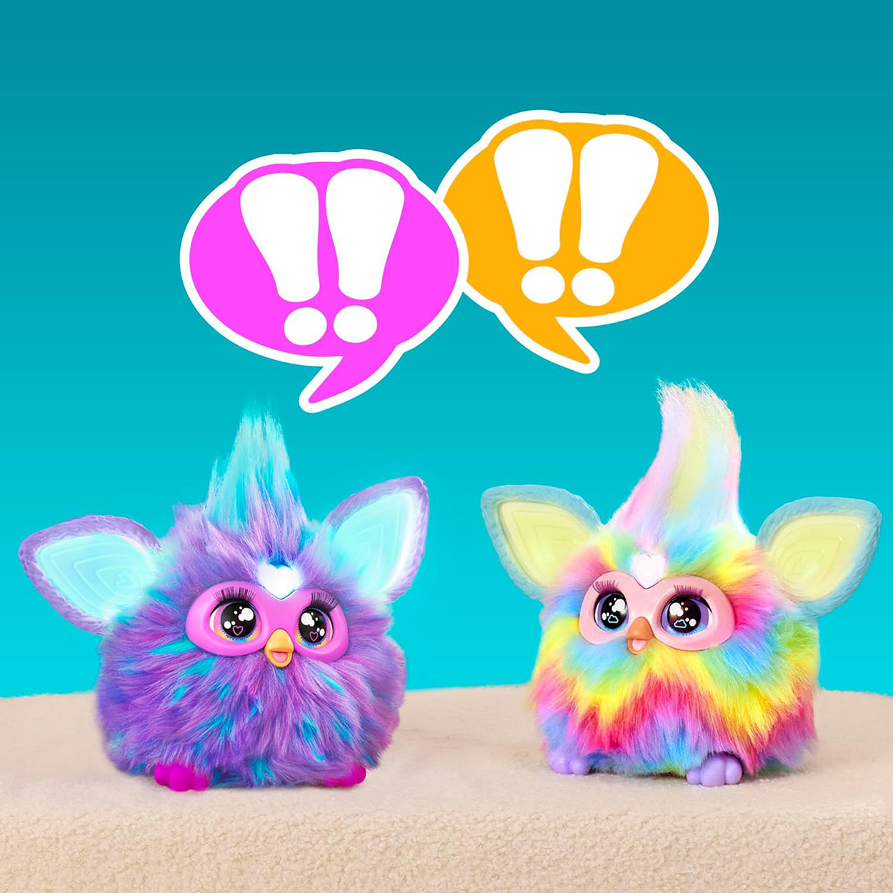 Zwei bunte Furby-Spielzeuge mit Sprechblasen darüber.