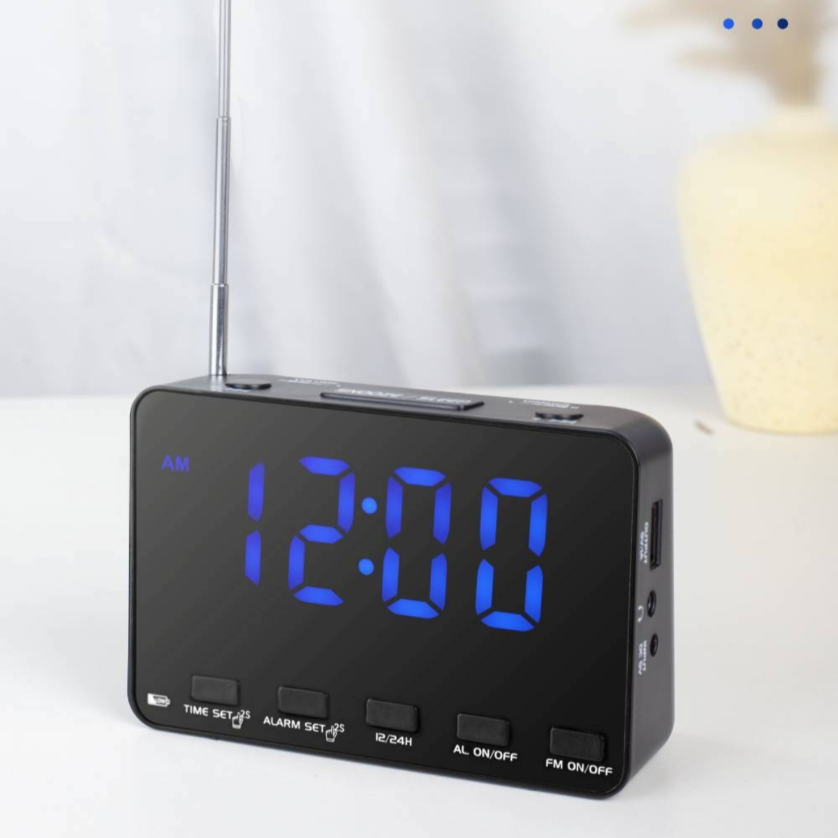 Eine schwarze Digitaluhr zeigt 12:00 mit blauem Licht und verschiedenen Knöpfen darunter an.