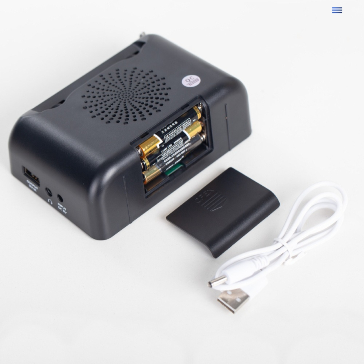 Schwarzes Radio mit Batterien und Ladekabel. Das Batteriefach ist geöffnet und zeigt die Batterien.