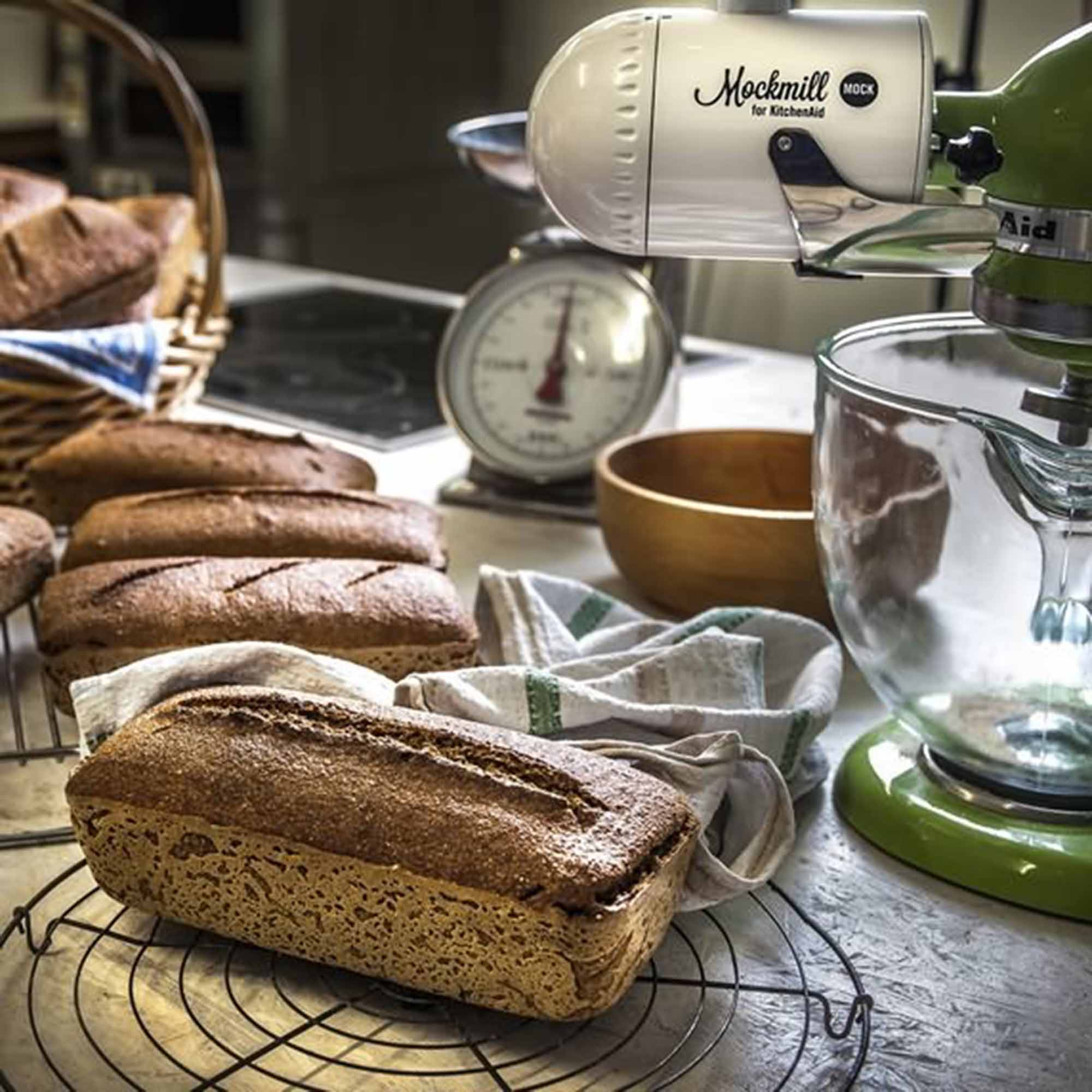 Zbliżenie na bochenki chleba, narzędzia do pieczenia i mikser w domowej kuchni.