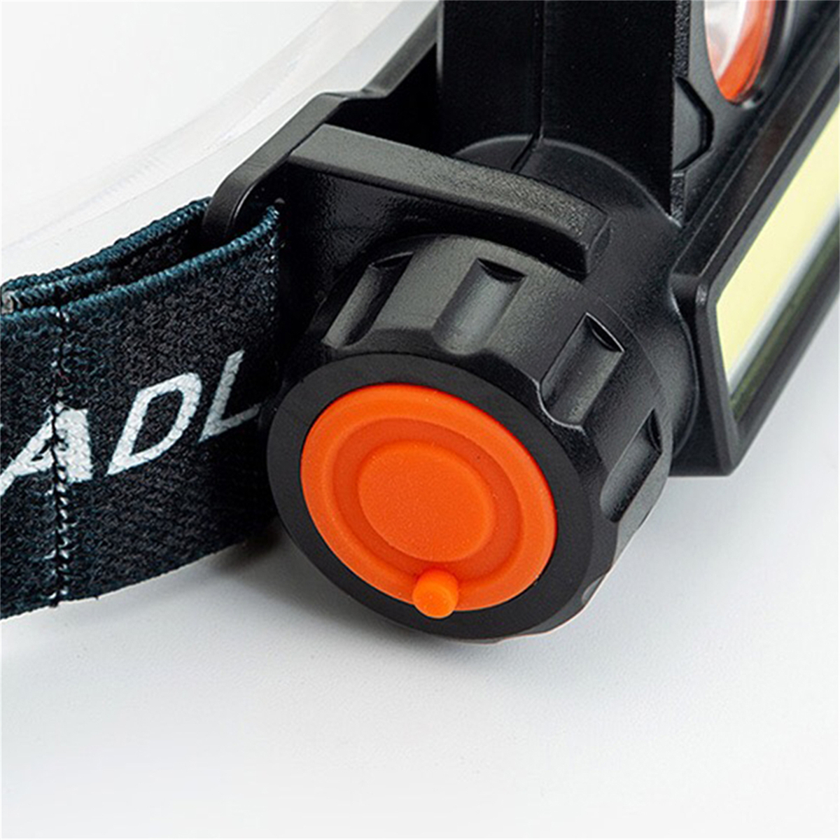 Nahaufnahme einer schwarz-orangenen Stirnlampe. Das orangefarbene Rad und der Riemen sind sichtbar.