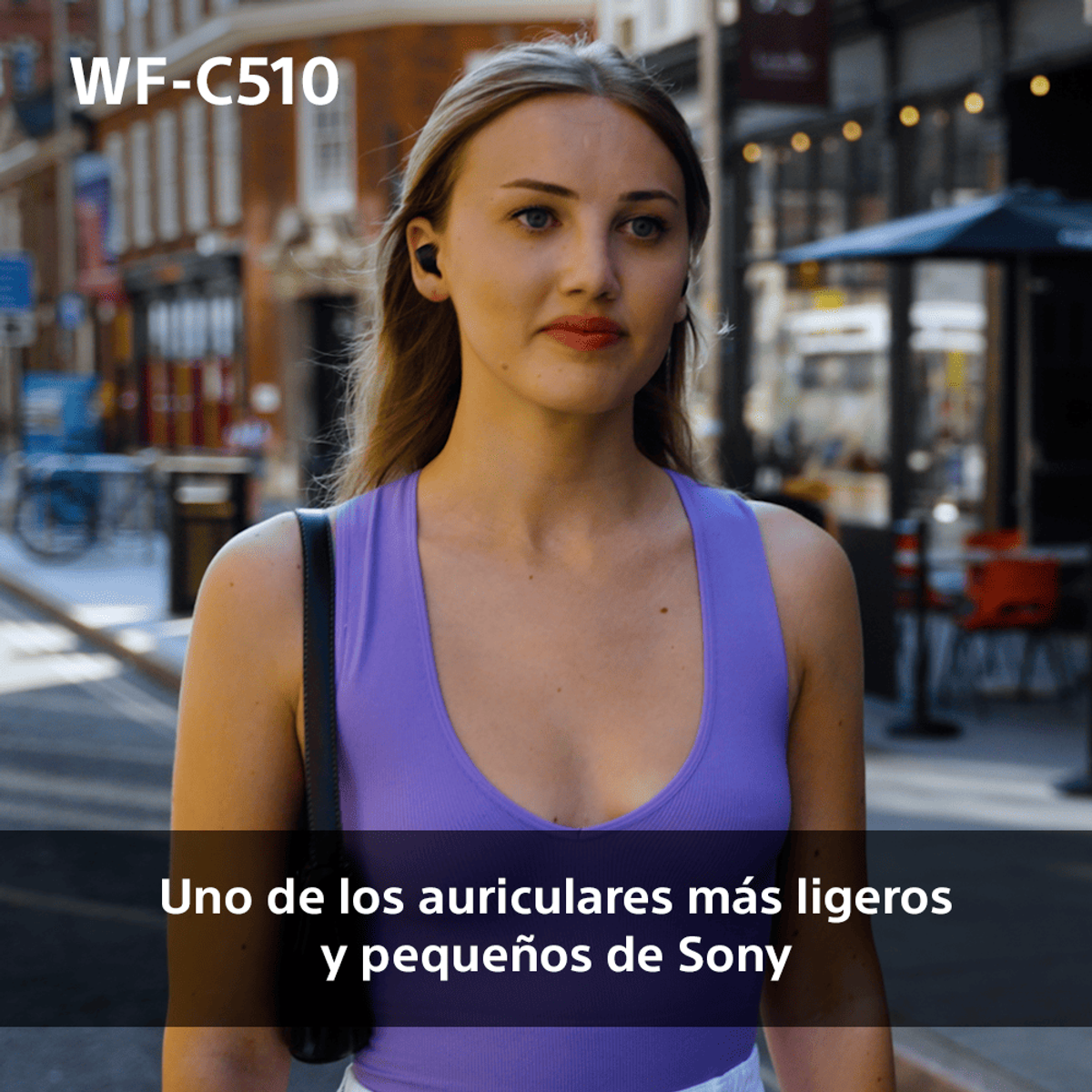 Frau mit Ohrhörern in der Stadt. Text: Einer der leichtesten und kleinsten Ohrhörer von Sony.