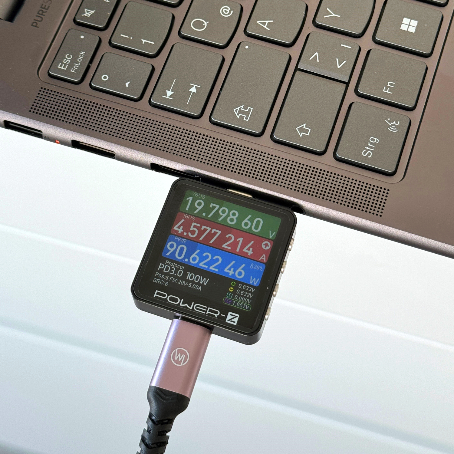 Ein Leistungsmesser, der über ein USB-C-Kabel mit einem Laptop verbunden ist. Meter zeigt Spannung und Strom.