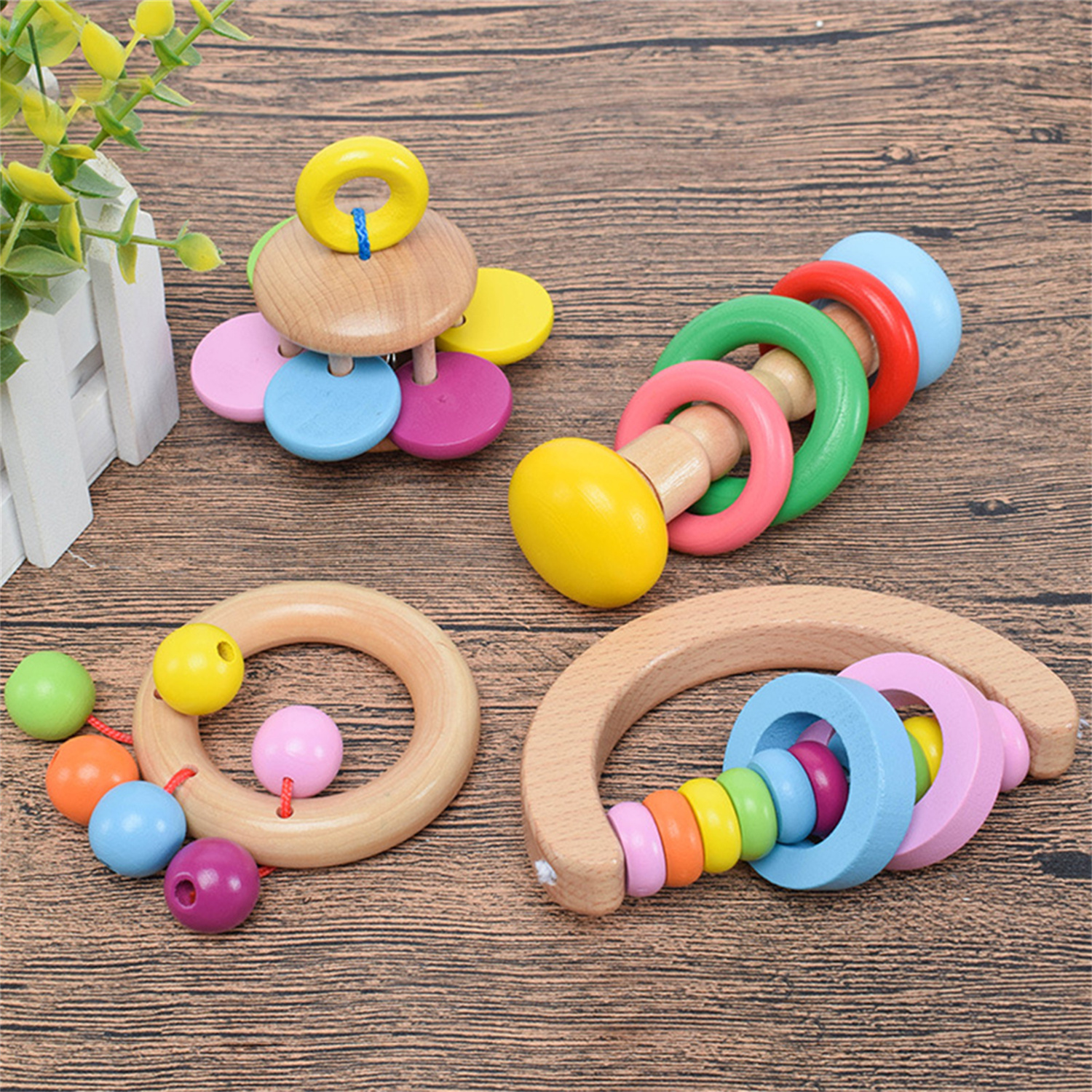 Holzspielzeug für Babys: Ringe, Perlen und eine gebogene Form, auf Holzoberfläche, verschiedene Farben, Studioaufnahme.