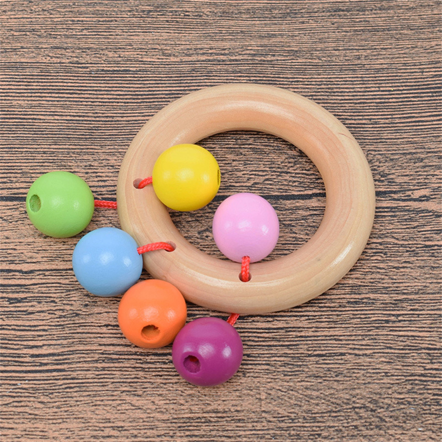 Holzspielzeug mit Holzring und bunten Kugeln, auf einer Holzoberfläche platziert.