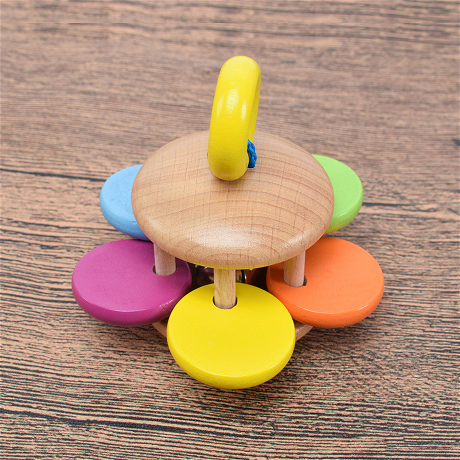 Holzspielzeug mit farbigen Kreisen. Der zentrale Kreis hat einen gelben Griff.
