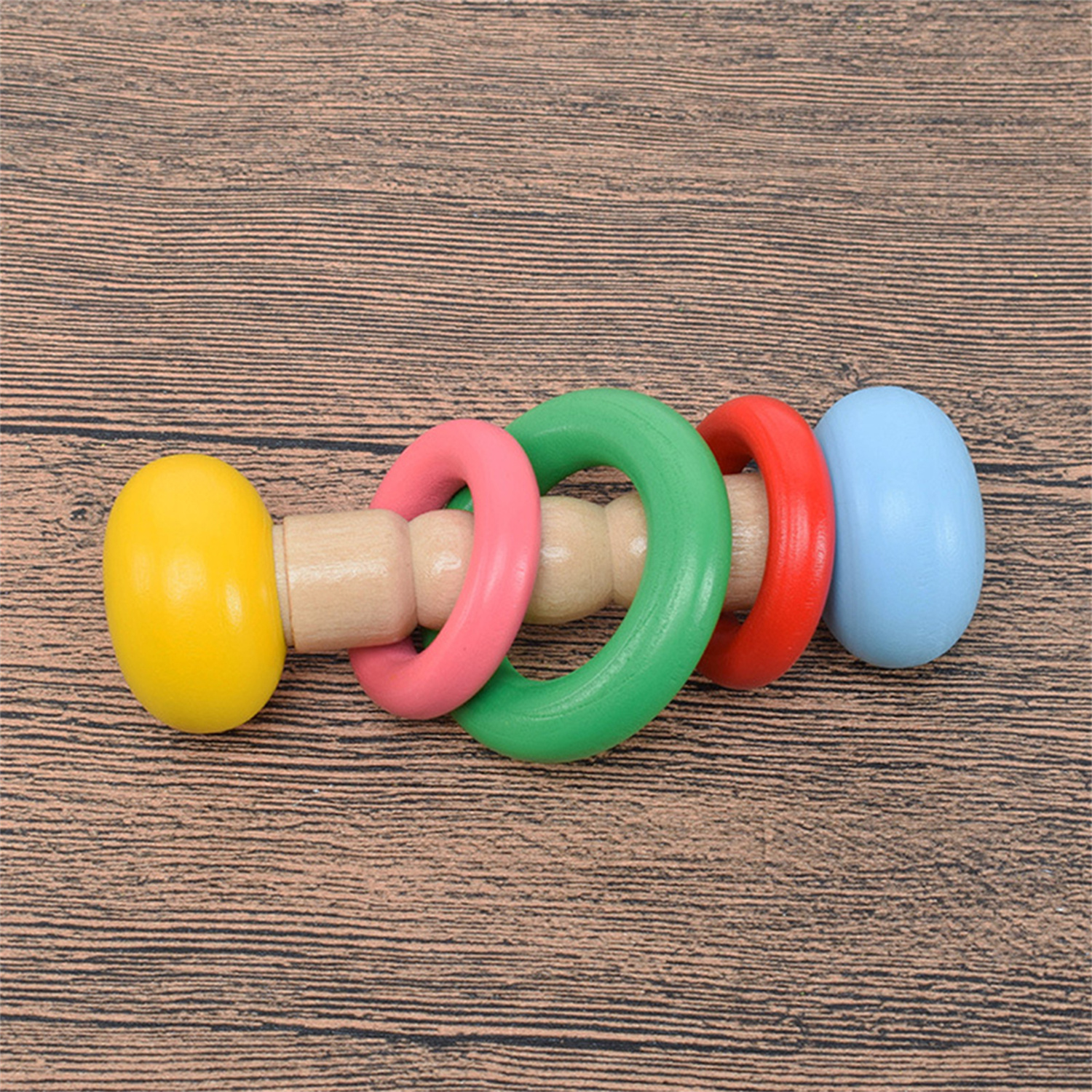 Holz-Steckspielzeug mit gelben, rosa, grünen, roten und blauen Ringen.