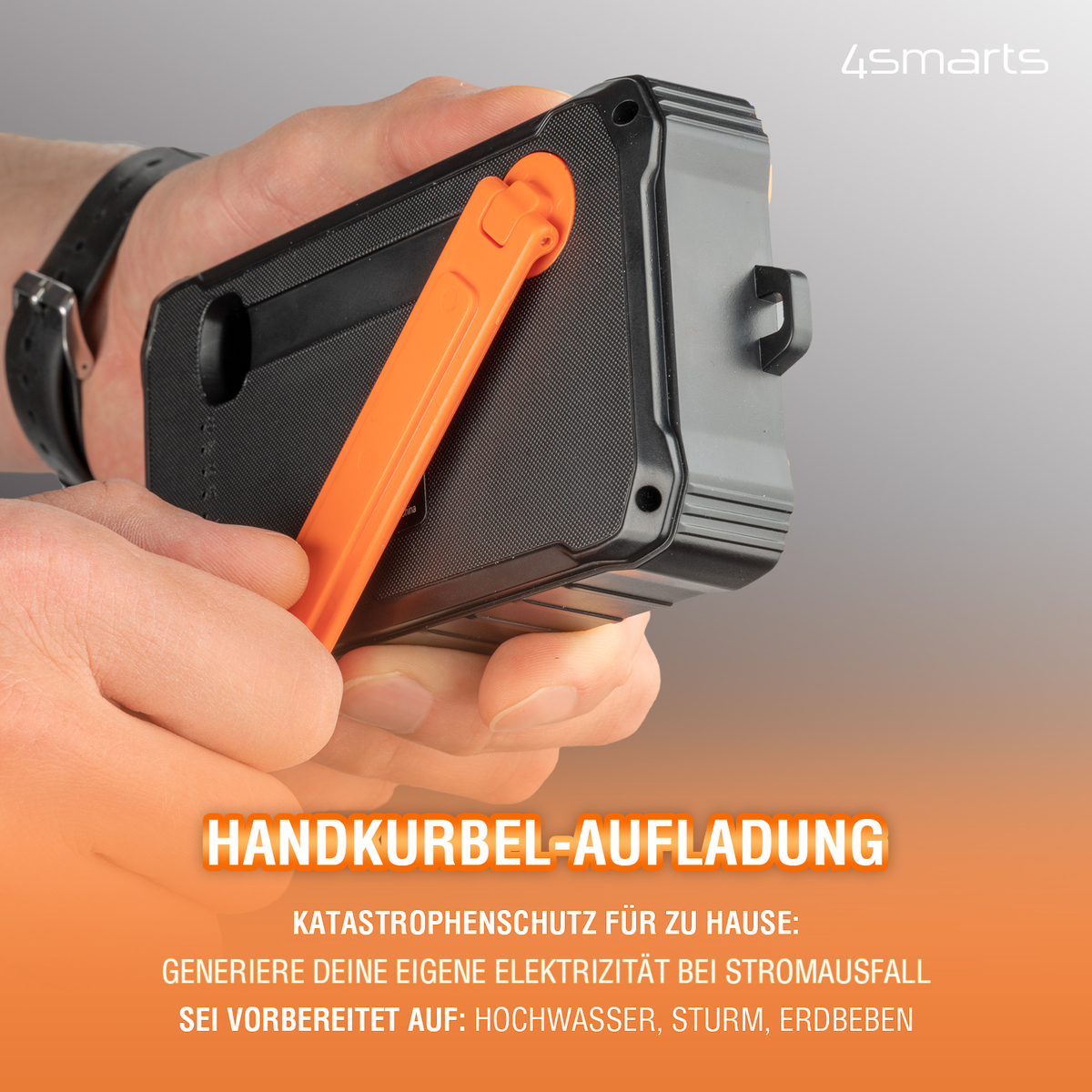 Hand hält ein schwarz-oranges Gerät. Text: HANDKURBEL-AUFLADUNG, GENERIERE DEINE EIGENE ELEKTRIZITÄT.