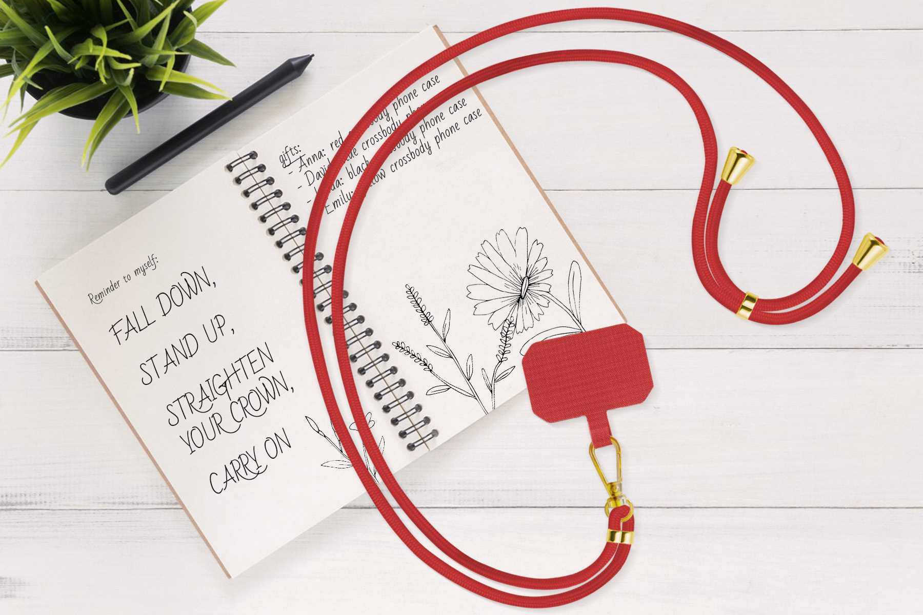 Rotes Telefon-Umhängeband, Notizbuch und Stift auf weißer Holzoberfläche.