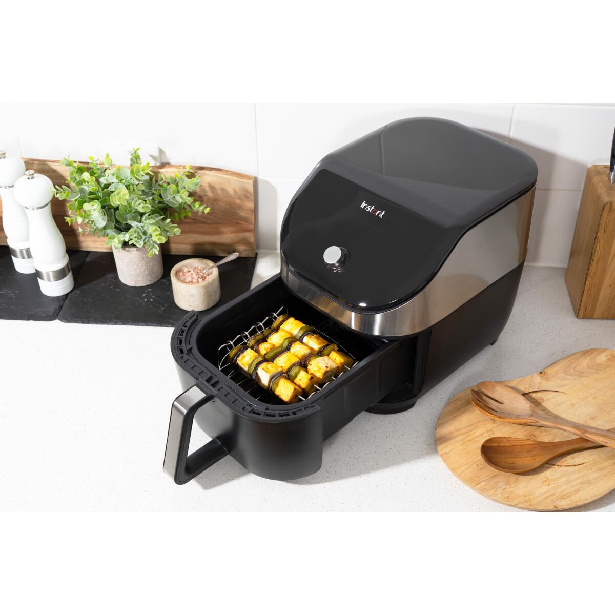 Instant Pot airfryer met eten erin. Open lade met spiesjes. Keukenomgeving.