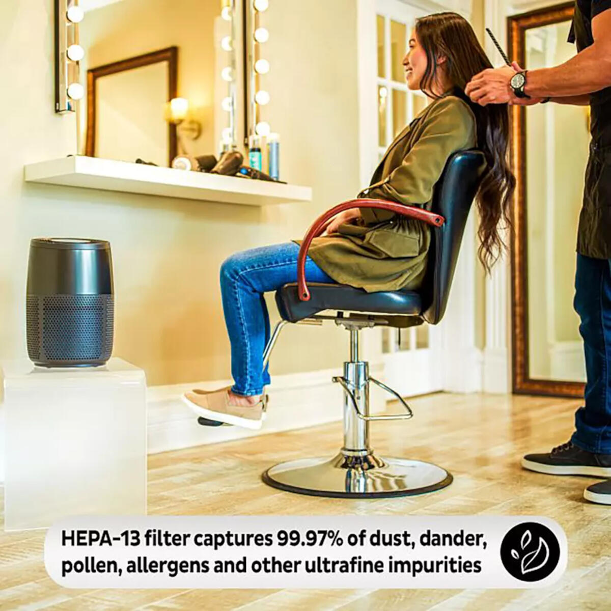 Eine Frau im Salon bekommt ihre Haare gestylt. Ein Luftreiniger steht links, ein Mann stylt ihr Haar.