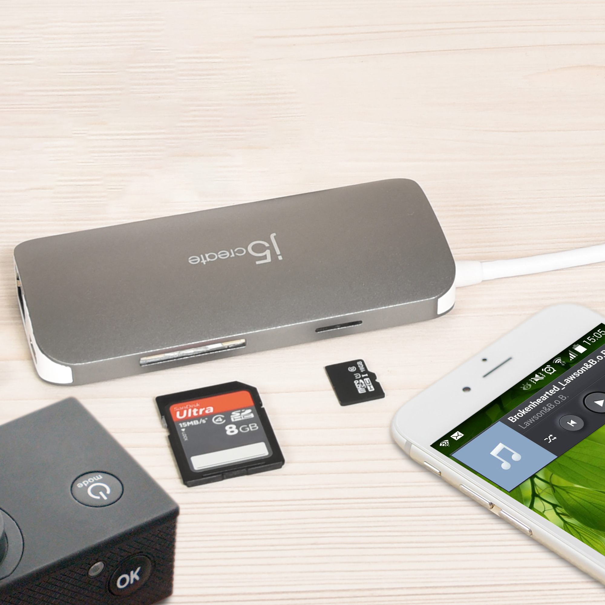 Ein silberner USB-Hub mit SD-Karten, einer microSD-Karte und einem Telefon auf Holzoberfläche.