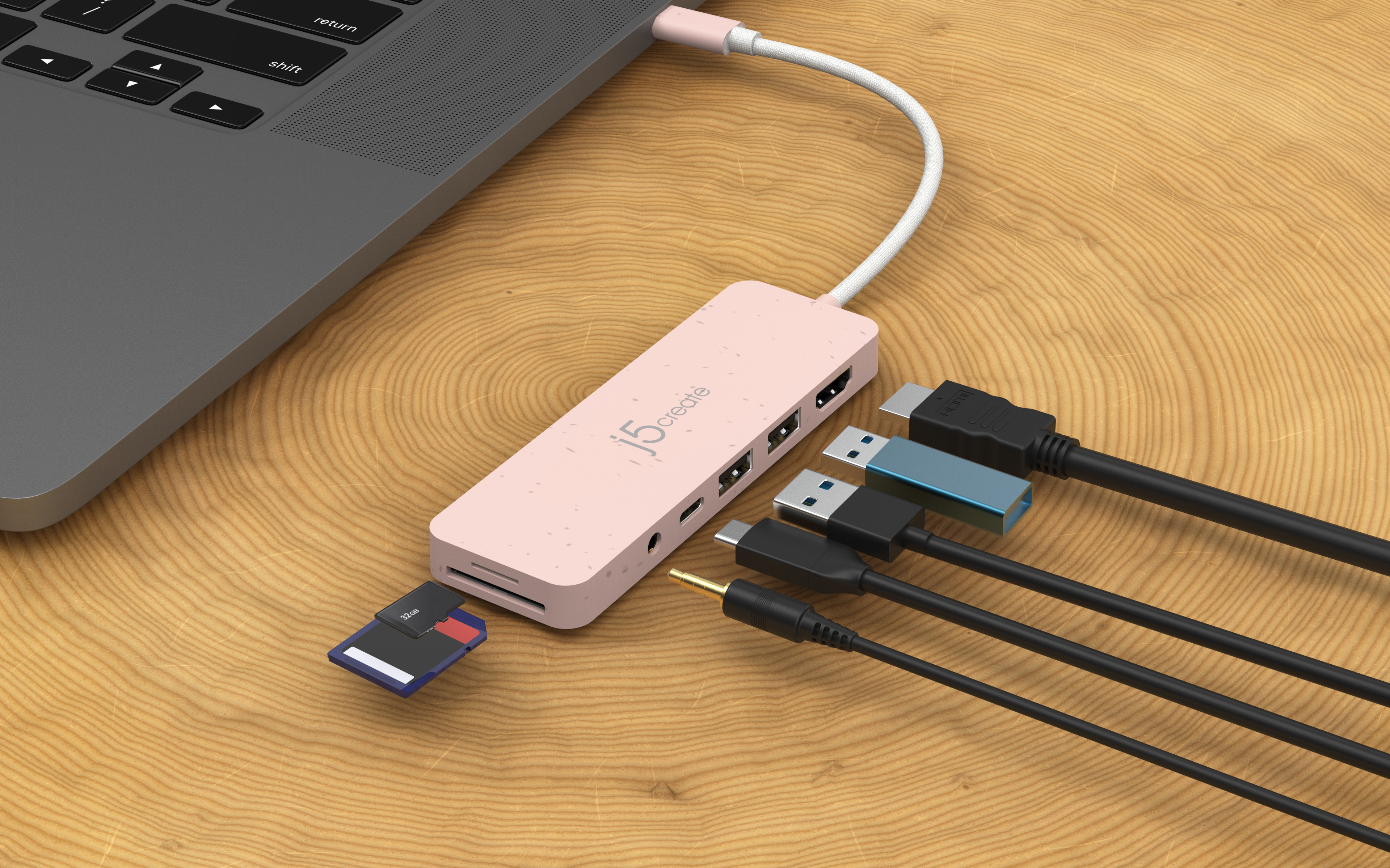 Rosafarbener Multiport-Hub mit SD-Karte und mehreren Kabeln, die an einen Laptop angeschlossen sind.