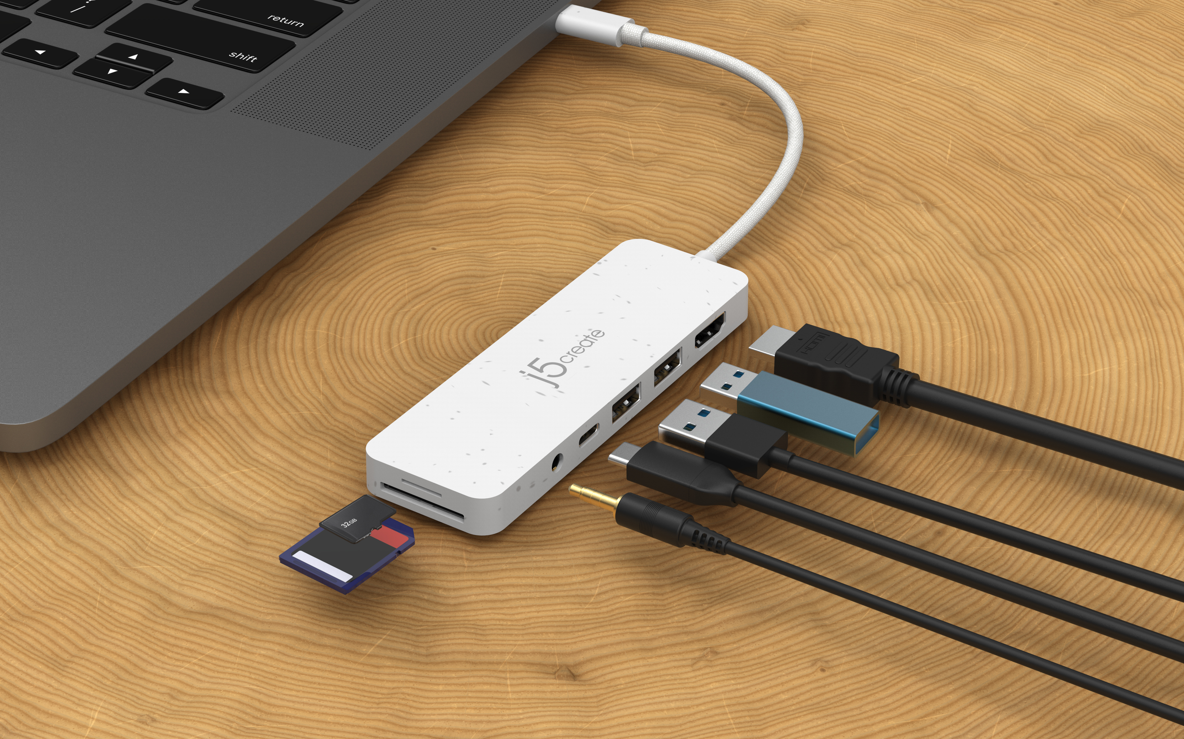 Laptop collegato a un hub con vari cavi e una scheda SD. Superficie in legno.