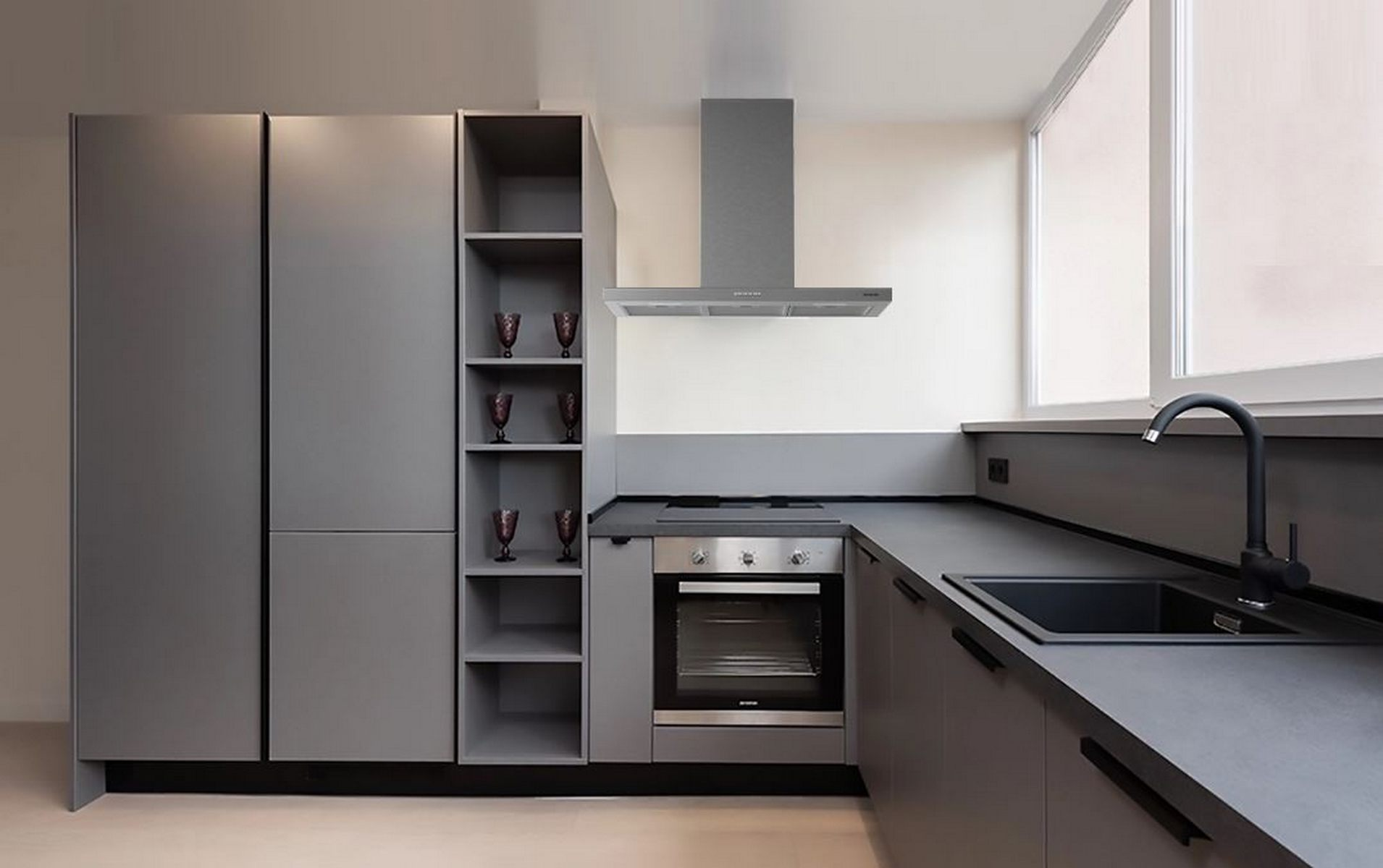Cocina gris moderna con armarios, un horno y un fregadero. Una ventana está a la derecha.