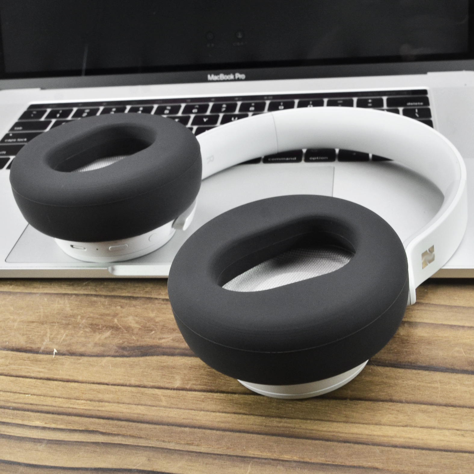 Białe słuchawki z czarnymi nausznikami na klawiaturze laptopa.