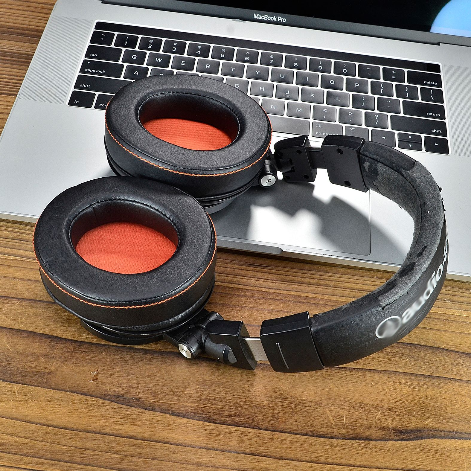 Schwarze Kopfhörer auf einem Laptop. Orangefarbene Ohrpolster.