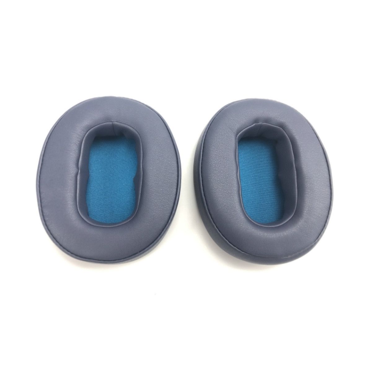 Dwie niebieskie poduszki na uszy na białej powierzchni. Poduszki są owalne.