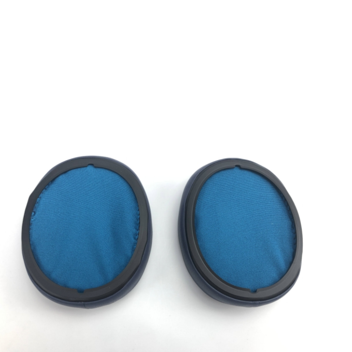 Dwie niebieskie, okrągłe nauszniki z czarnymi obwódkami, na białym tle.