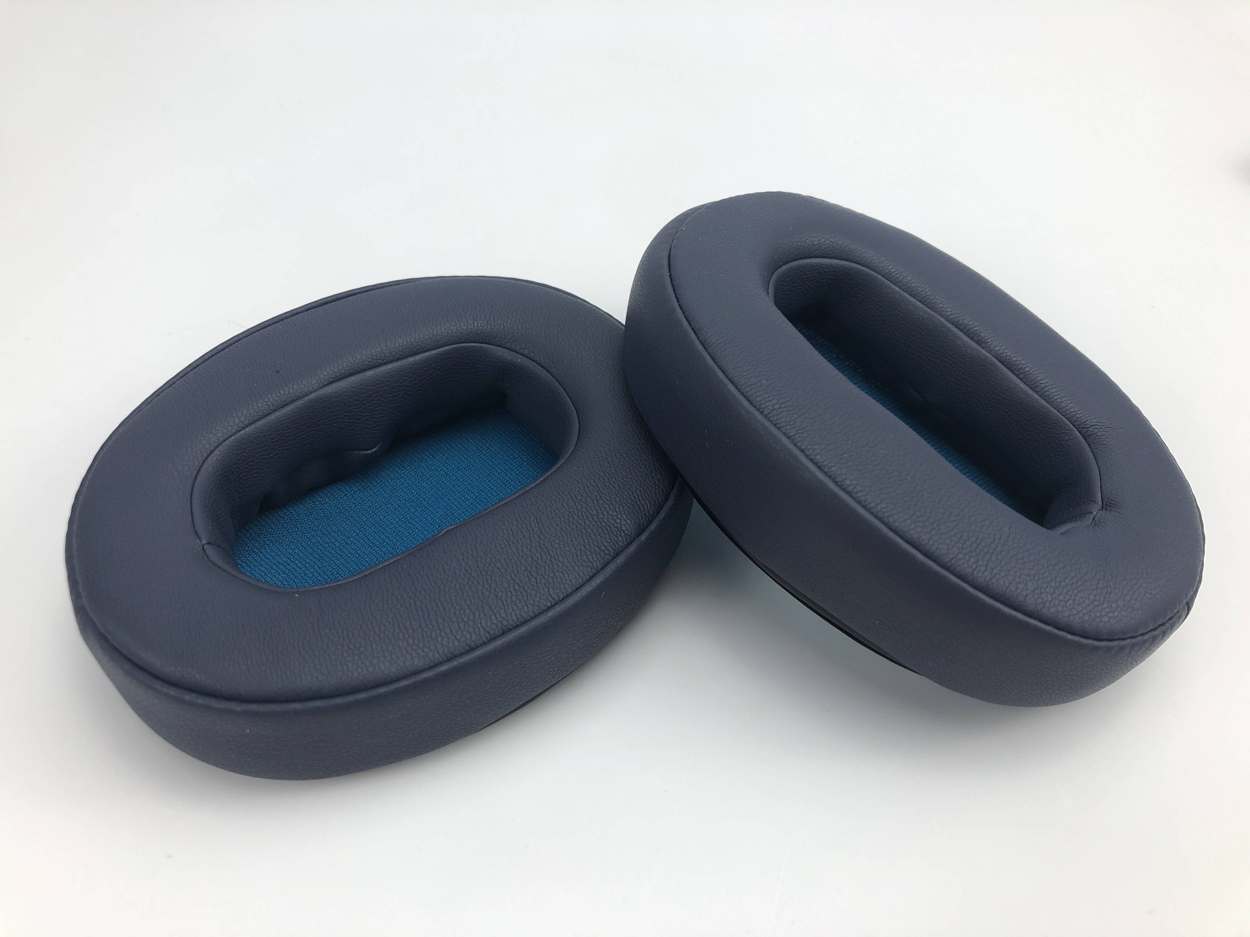 Dwie granatowe poduszki na uszy z niebieskim wnętrzem z siatki.