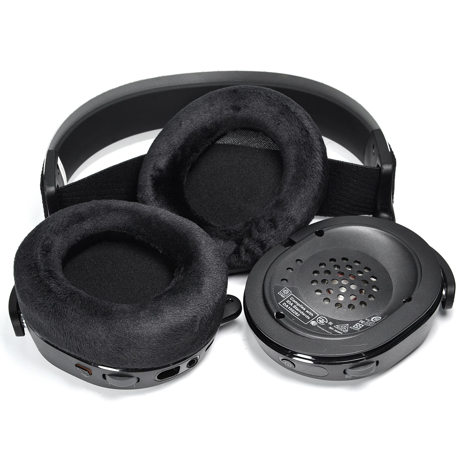 Hoofdtelefoononderdelen, oorschelpen en hoofdband, zwart, op wit oppervlak.