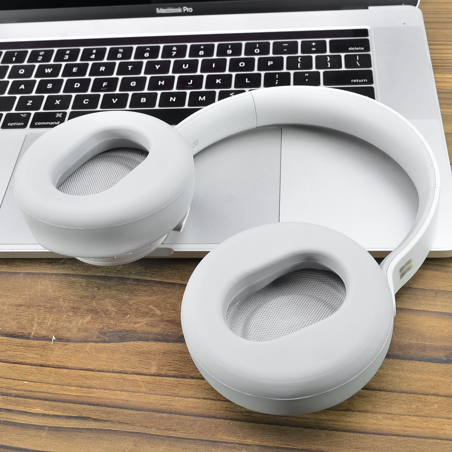 Białe słuchawki spoczywające na klawiaturze laptopa.