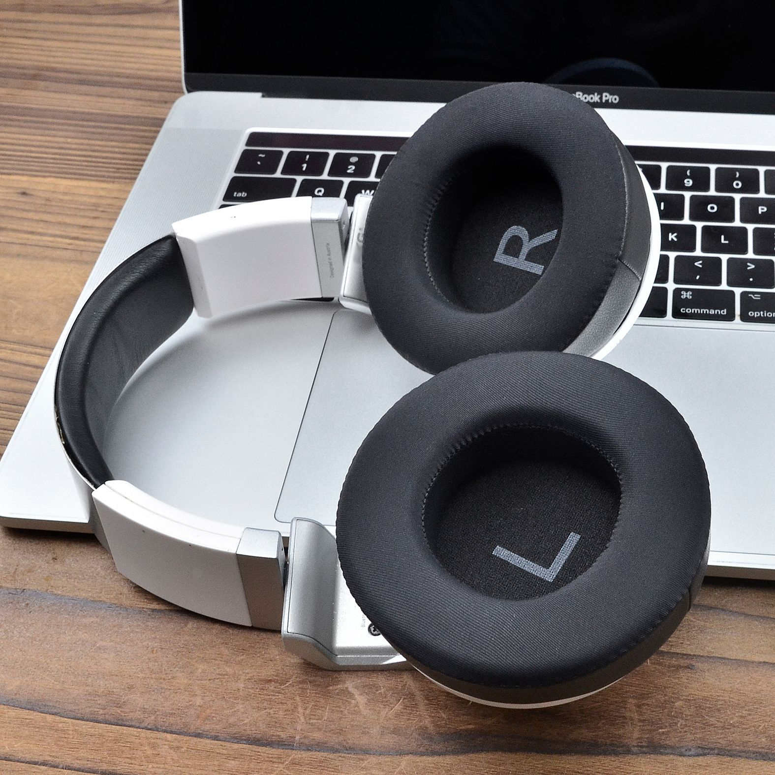 Widok z góry na białe i szare słuchawki na klawiaturze laptopa, z czarnymi nausznikami.