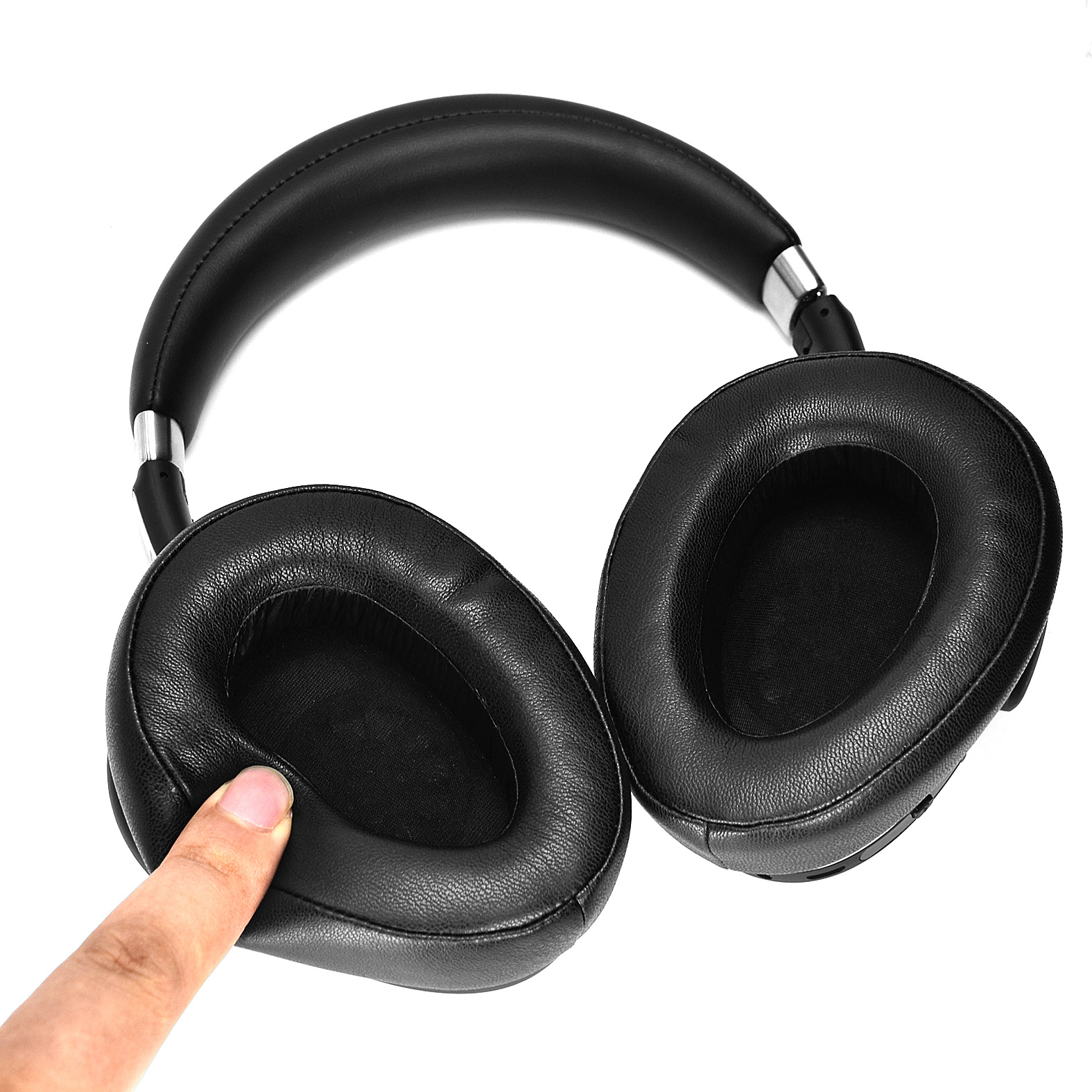 Schwarze Kopfhörer, wobei ein Finger eine der Ohrmuscheln berührt.
