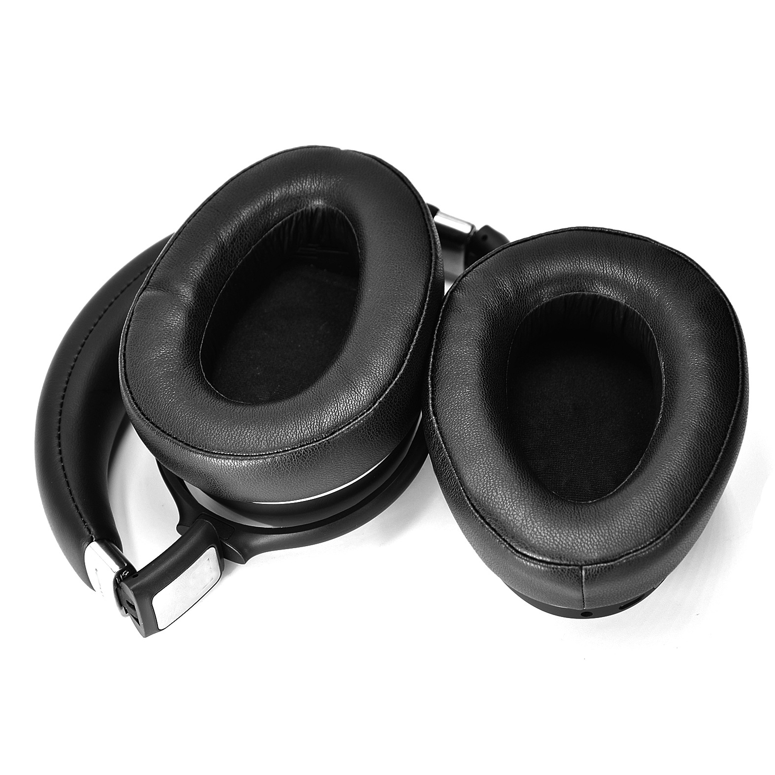 Schwarze Over-Ear-Kopfhörer mit großen, weichen Ohrmuscheln. Die Kopfhörer liegen auf einer weißen Oberfläche.