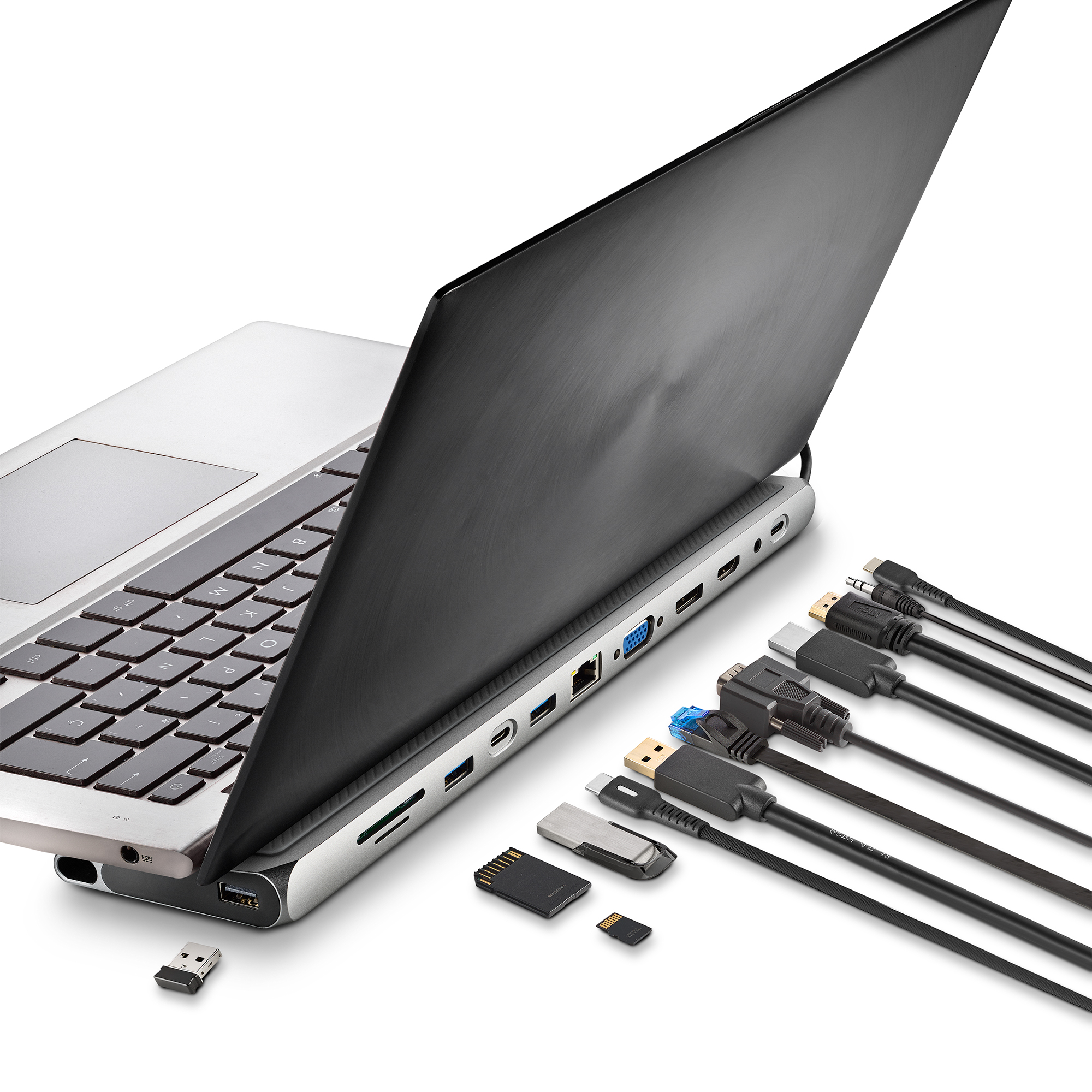 Laptop mit mehreren angeschlossenen Kabeln und Zubehör auf weißer Oberfläche.