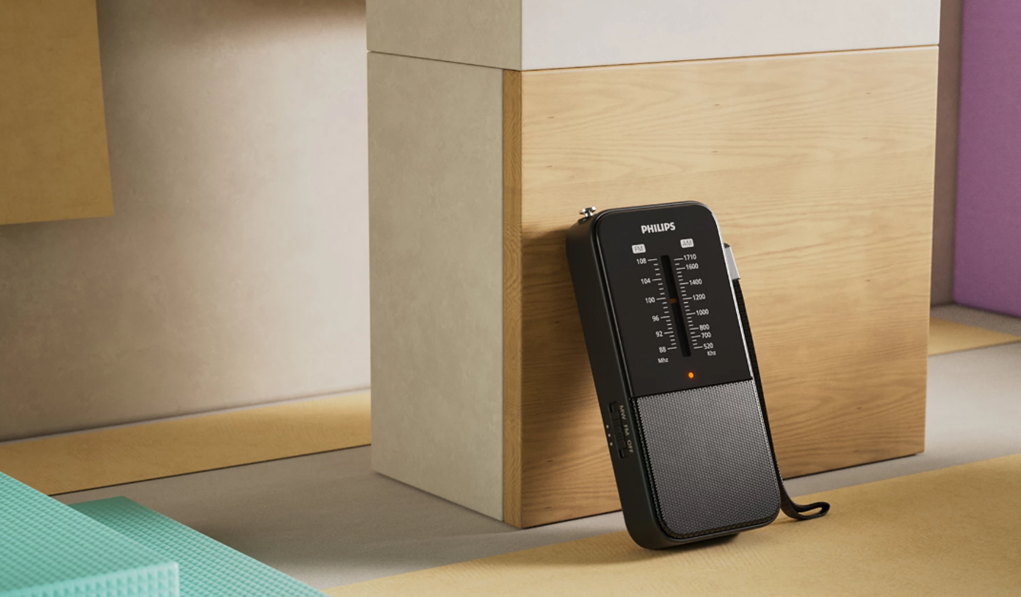Czarny przenośny radioodtwarzacz Philips na kolorowej powierzchni, obok ściany.