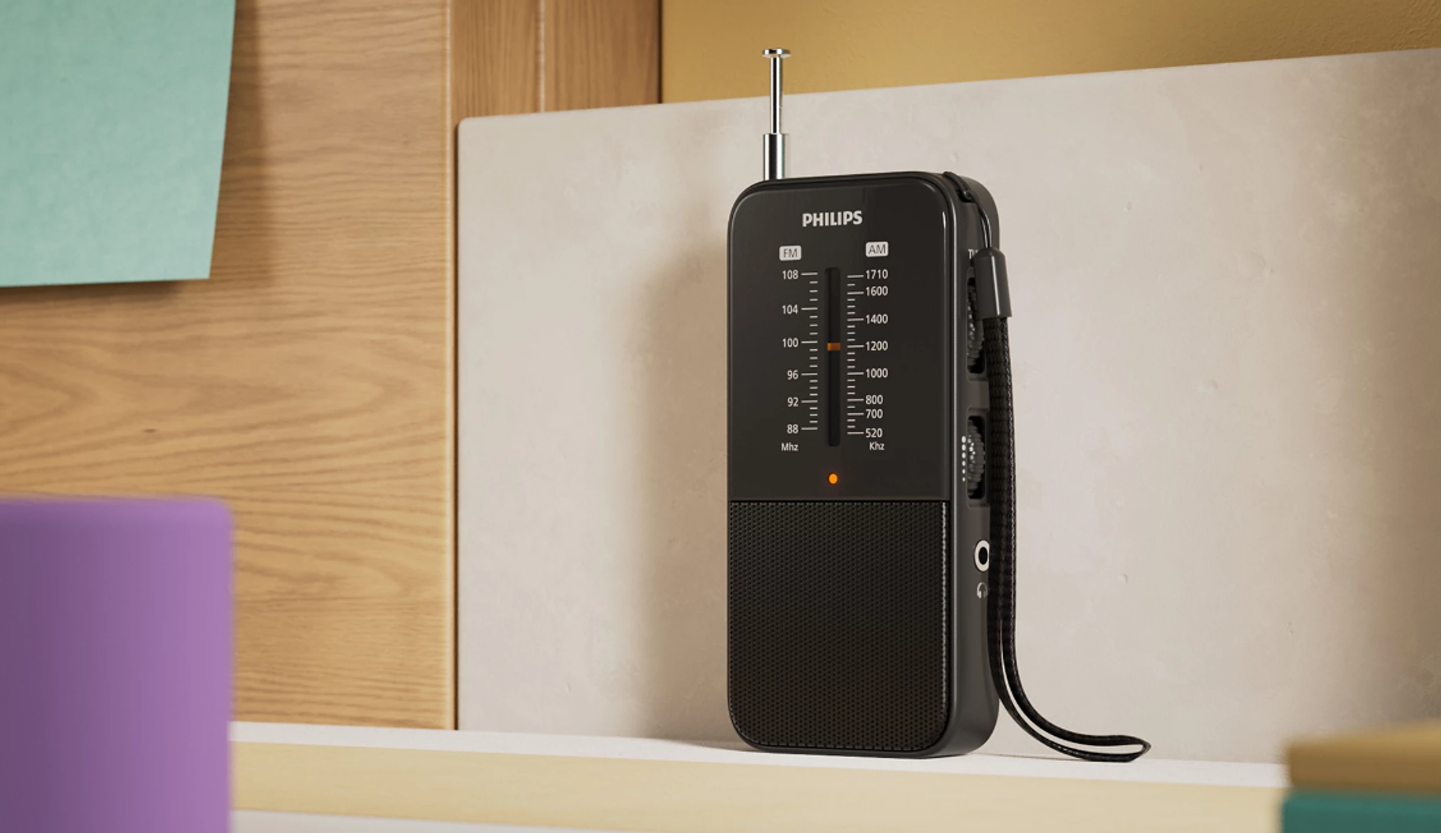 Czarny radio Philips na półce. Ma antenę i pokrętło strojenia.