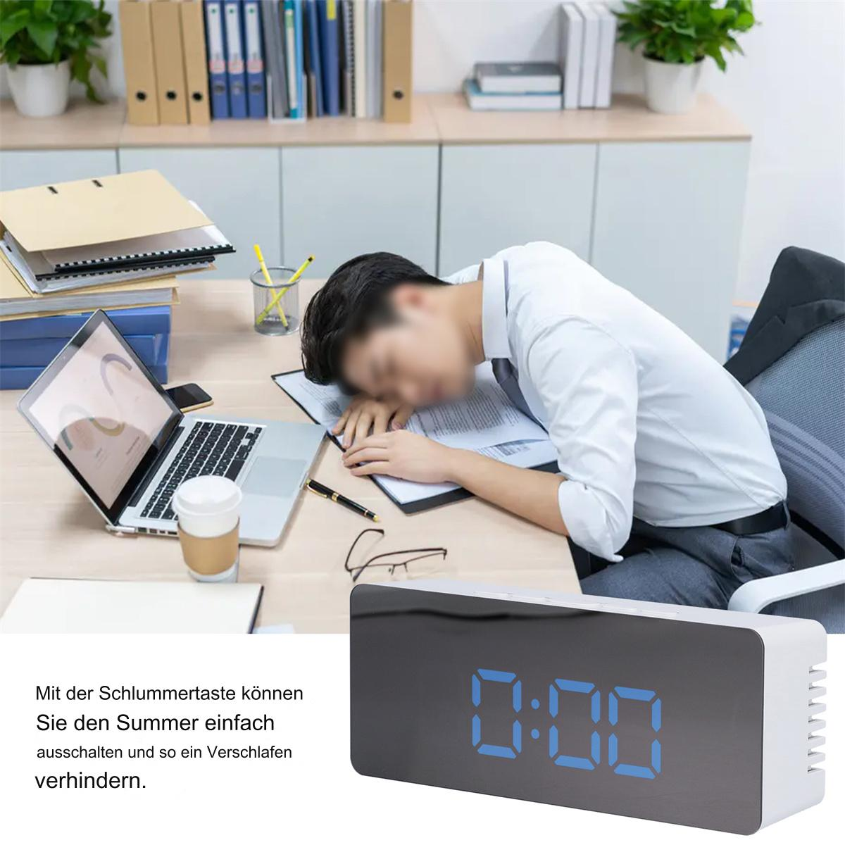 Mann schläft am Schreibtisch mit Digitaluhr.