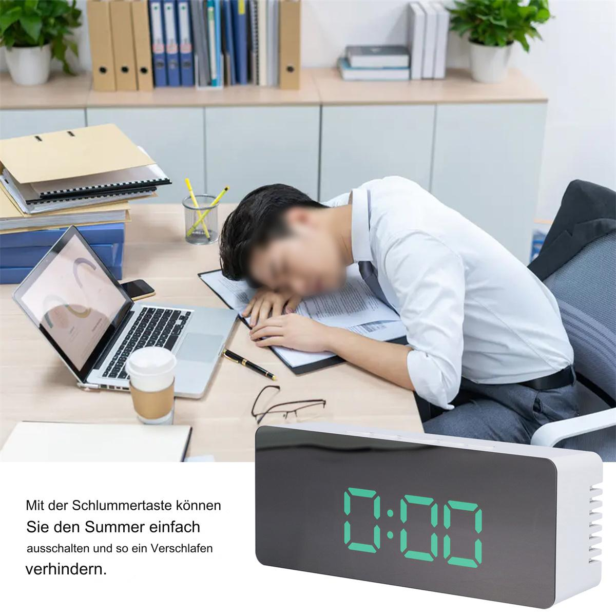 Ein Mann schläft am Schreibtisch, mit einer Digitaluhr, die 0:00 anzeigt.