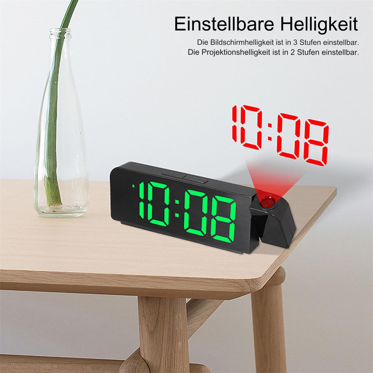 Schwarze Digitaluhr mit grüner Anzeige. Sie projiziert die Zeit in Rot auf eine Holzoberfläche.