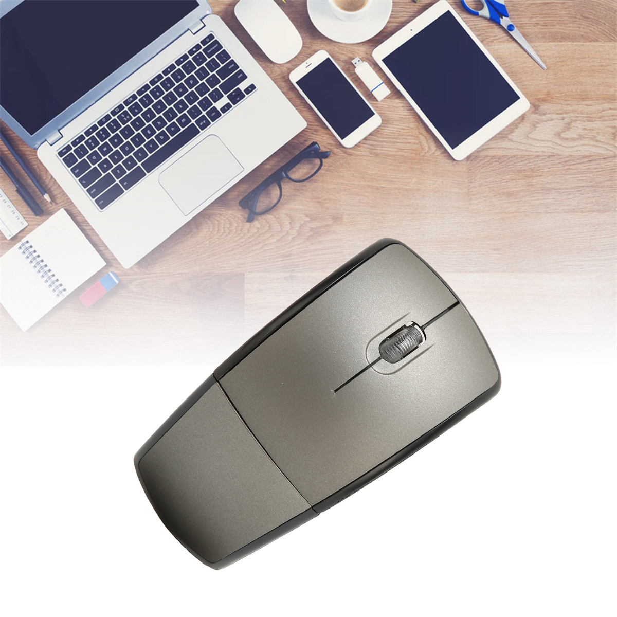 Graue Computermaus auf einem Schreibtisch mit Laptop, Telefon, Tablet und Bürobedarf.