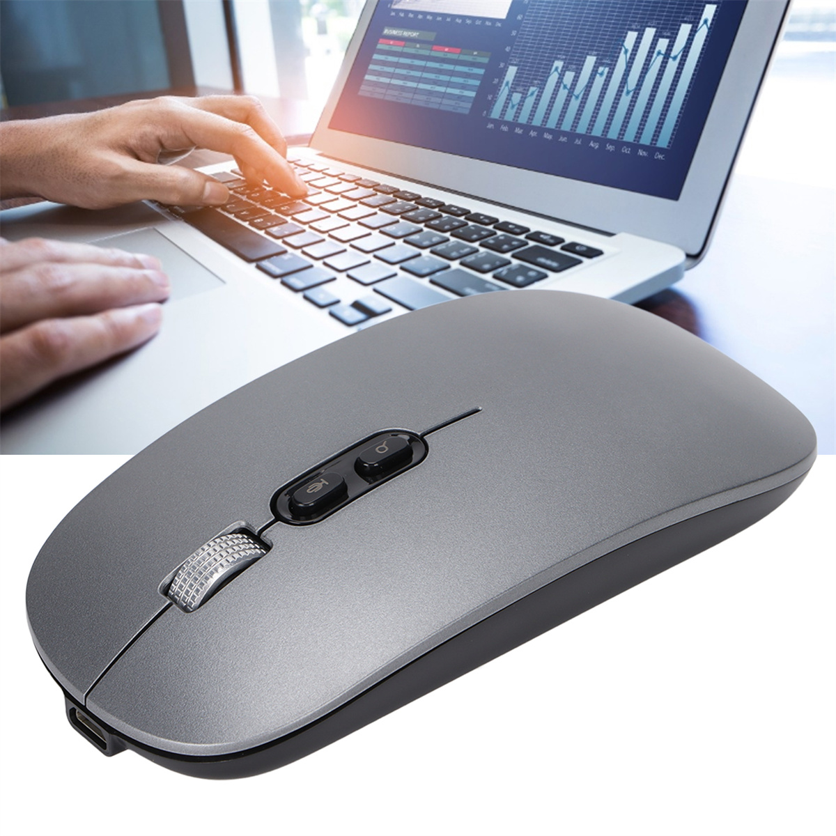 Eine graue Maus auf einem Schreibtisch mit einem Laptop im Hintergrund. Eine Hand benutzt die Maus.