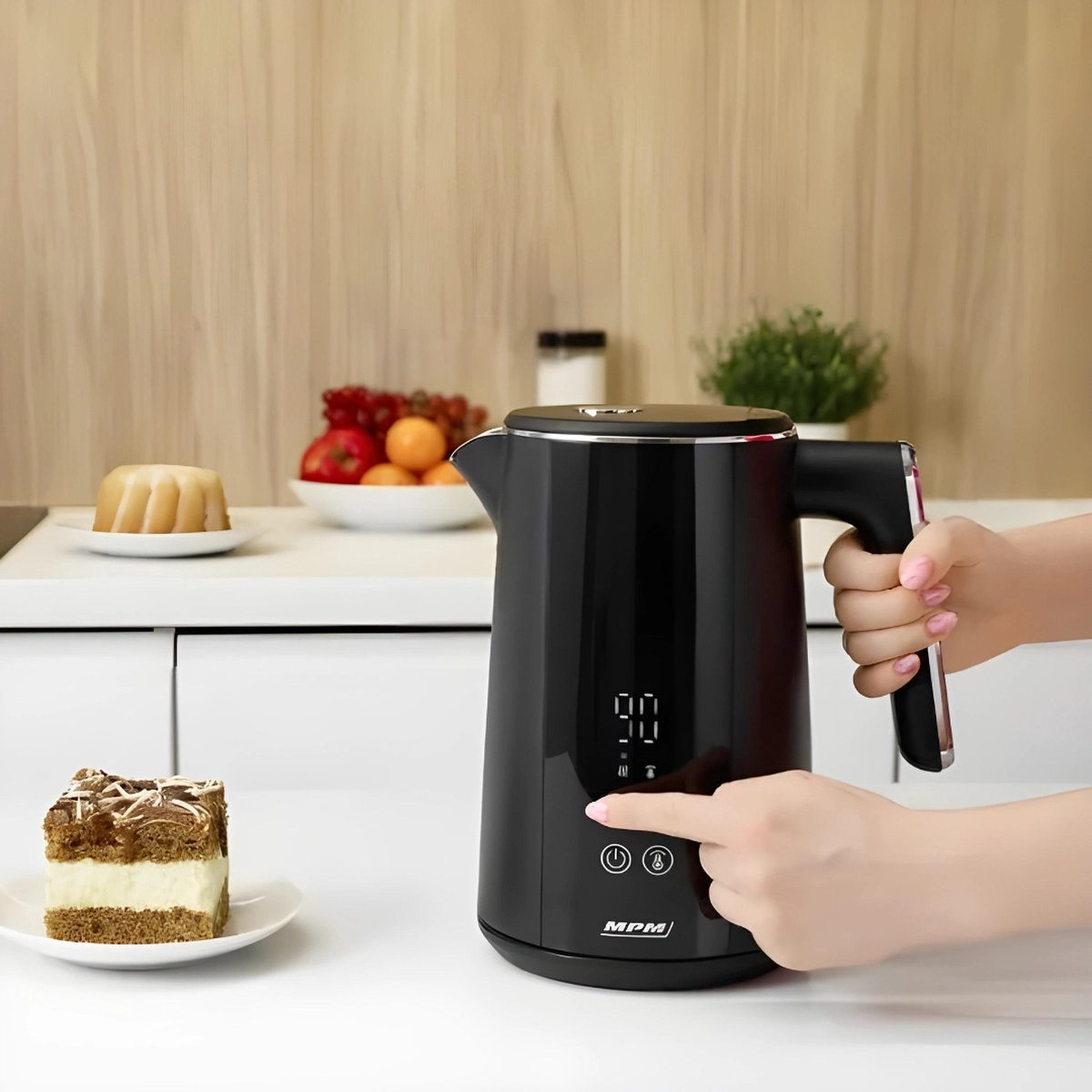 Schwarzer elektrischer Wasserkocher mit einer Hand, die einen Knopf drückt. Kuchenstück links.