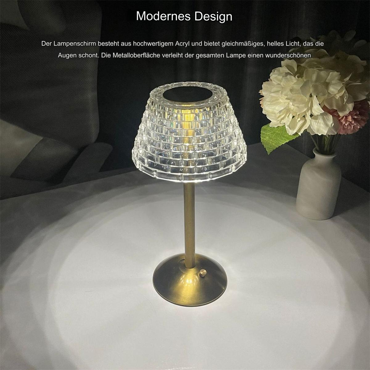Tischlampe mit transparentem Schirm und goldenem Fuß, Blumen daneben.