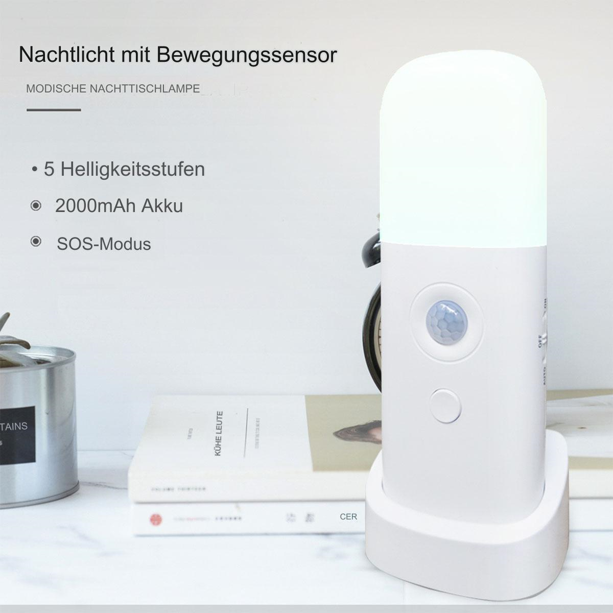 Weiße Nachttischlampe auf einem Ständer mit Buch und Pflanze auf dem Tisch.
