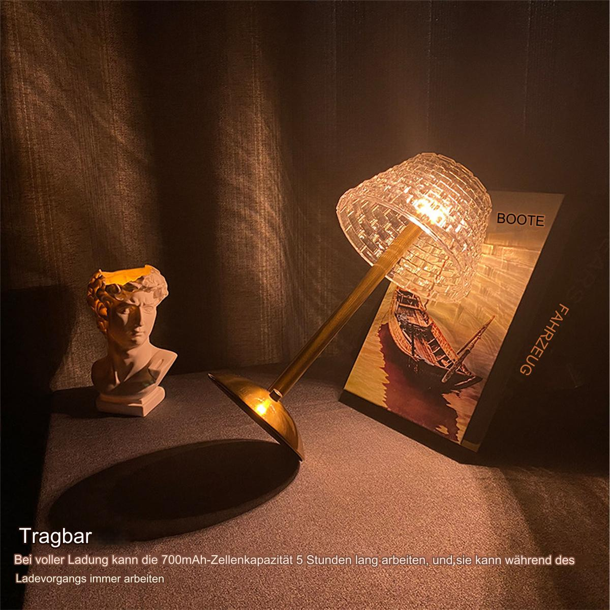 Lampe mit strukturiertem Glasschirm, Buch und Büste auf einem Tisch. Warmes, gedämpftes Licht.