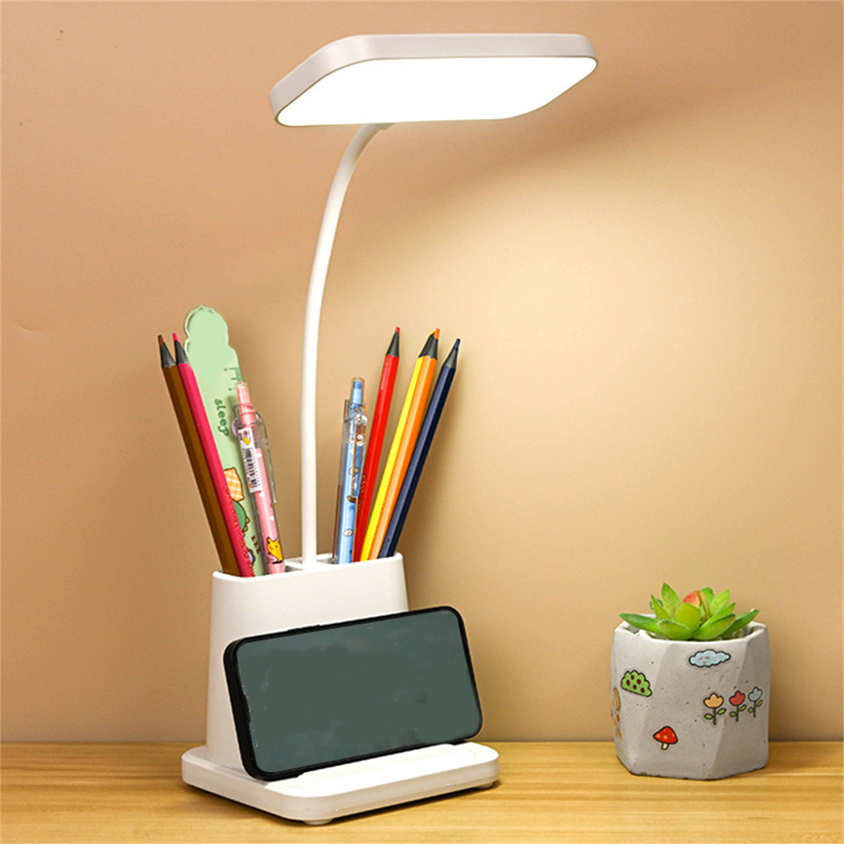 Eine Schreibtischlampe mit einem Stifthalter und einer kleinen Pflanze.