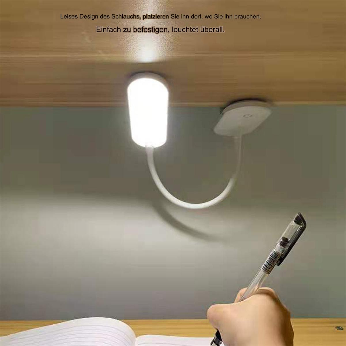 Eine weiße Schreibtischlampe ist an einem Schrank befestigt. Eine Hand schreibt mit einem Stift in ein Notizbuch.