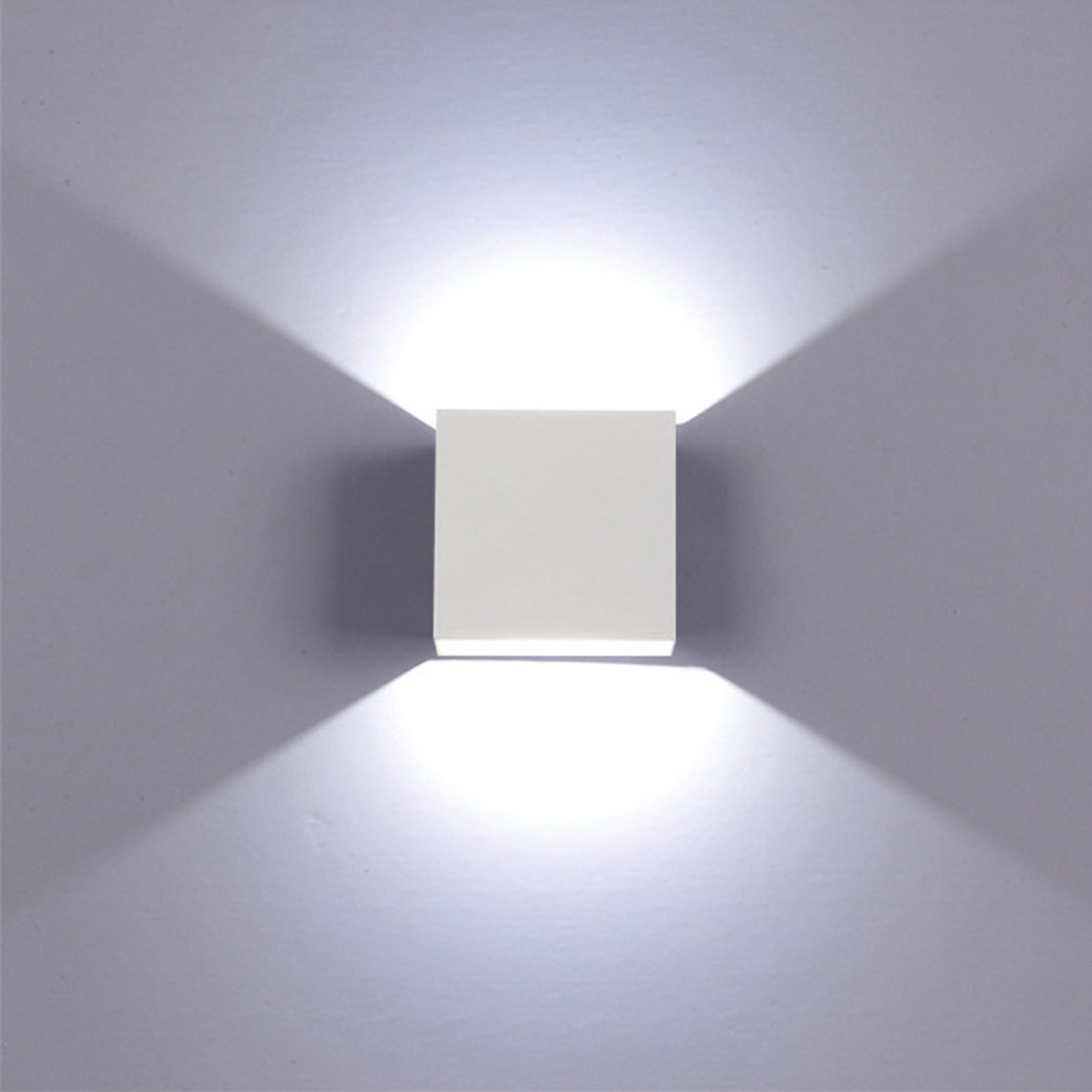 Weiße quadratische Wandleuchte, die Licht nach oben und unten auf einer grauen Wand ausstrahlt.