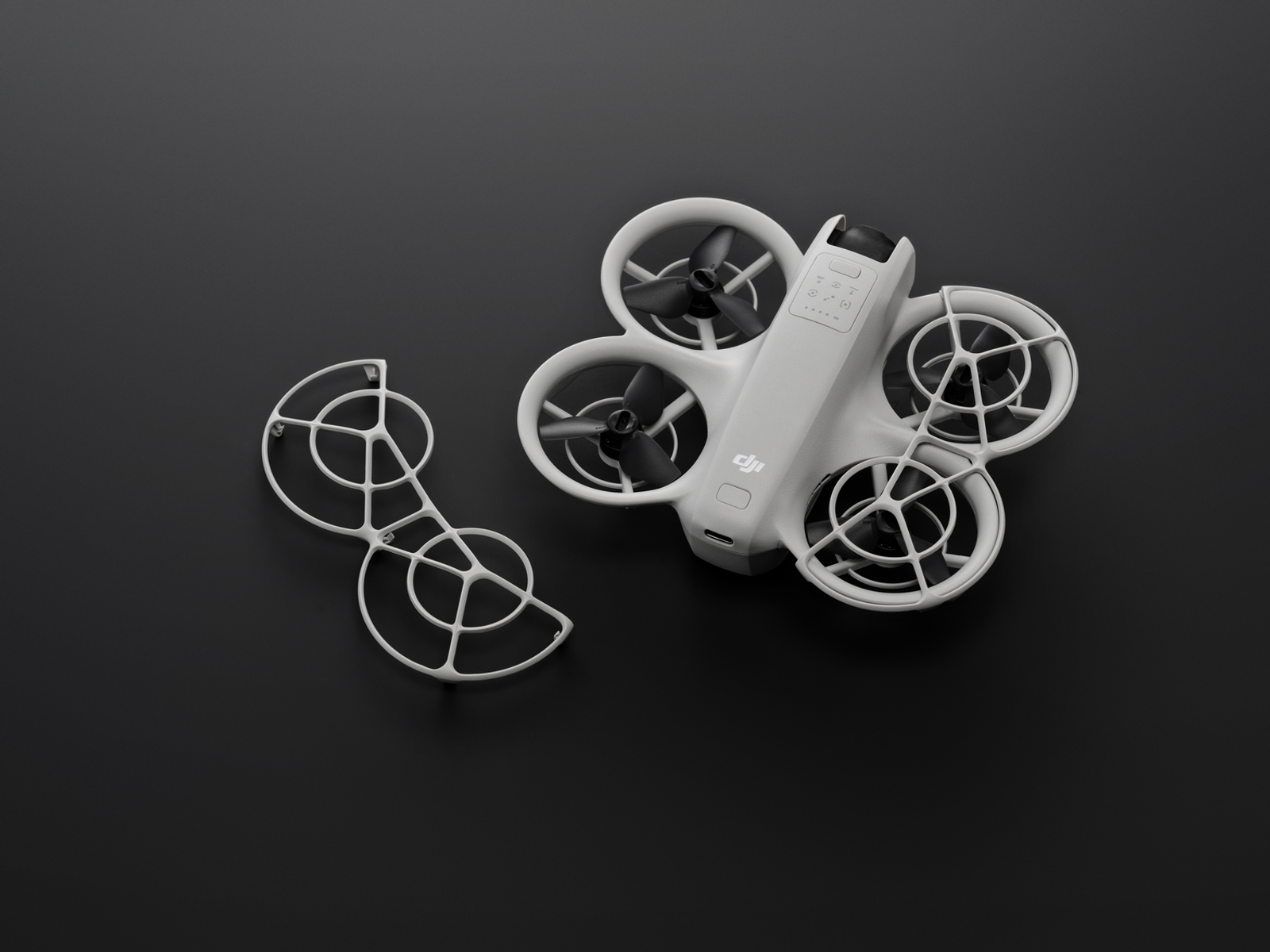 Drone bianco con quattro eliche e protezione dell'elica staccata su sfondo nero.